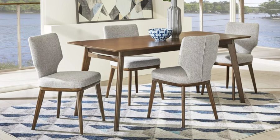 Midcentury modern dining chairs with soft gray upholstery surround a wood-finished table while a few pieces of tabletop decor add a subtle yet chic finishing touch.